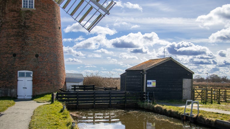 Image showing the view looking towards Horsey Windpump with the staithe and electric pumping station to the right which is housed in a painted black wooden shed like structure